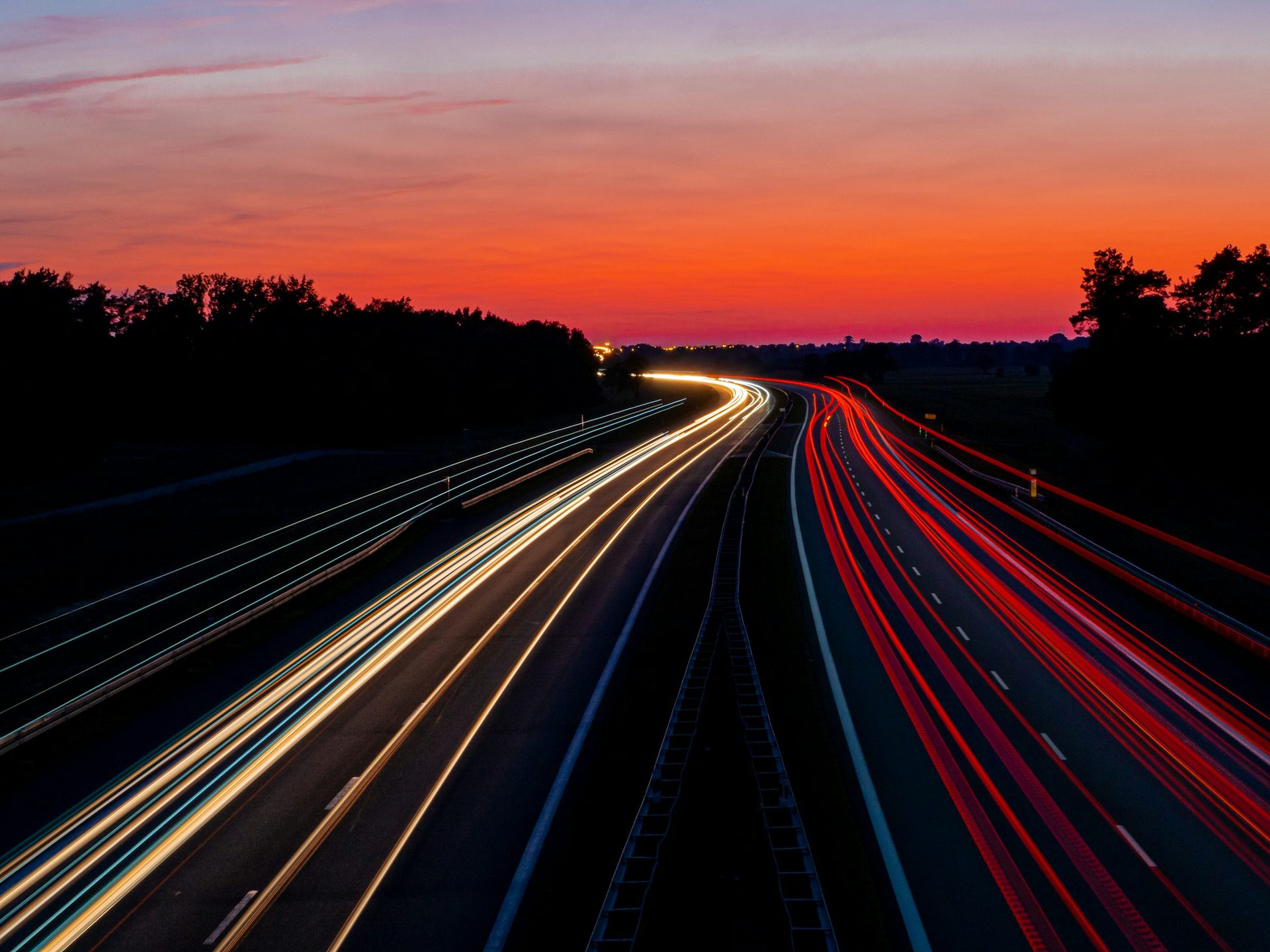 Long-exposure light trails on a highway at sunset